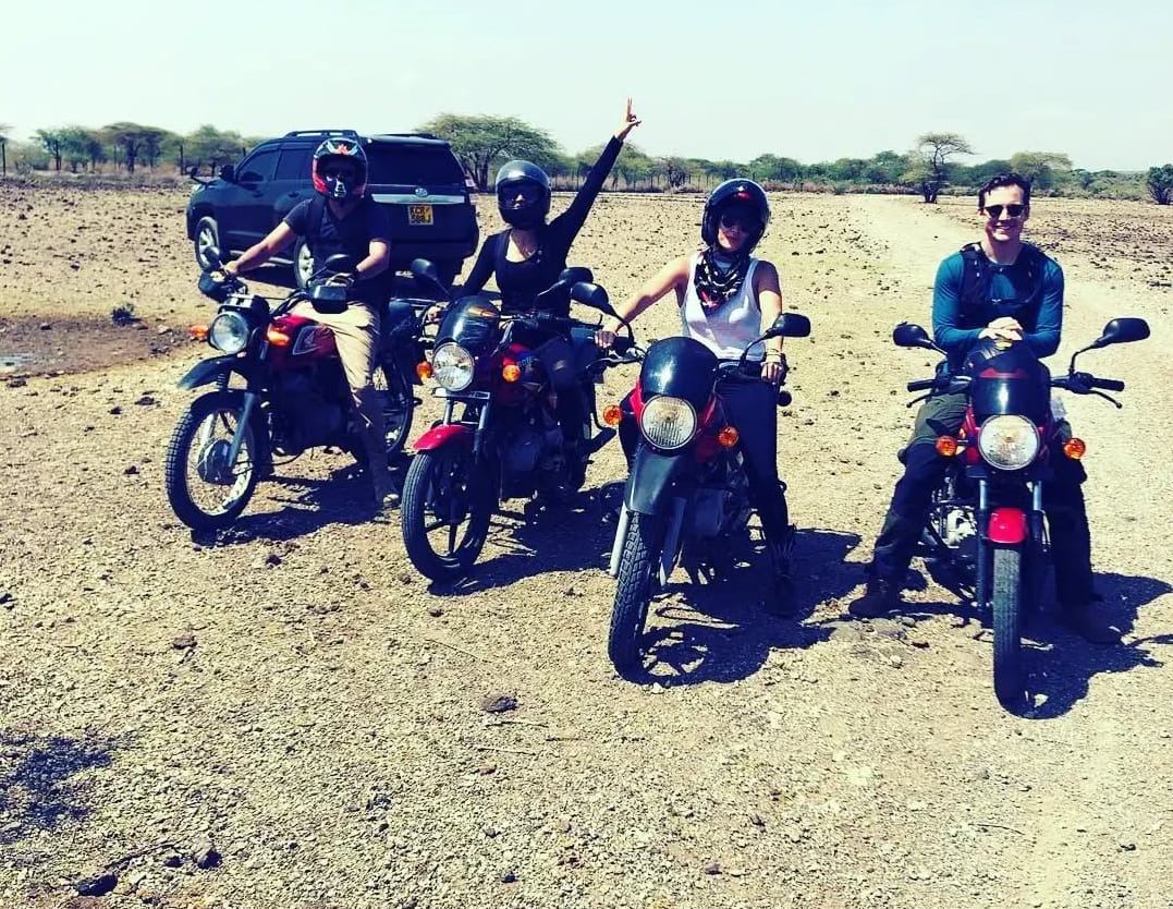 Four Osiligi motorbike riders with their bikes on a remote savanna track